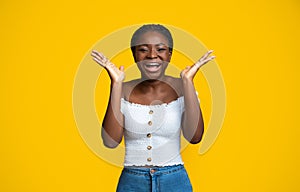 Cheerful African American Woman Laughing And Raising Hands In Excitement, Yellow Background
