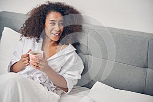 Cheerful African American woman sitting in bed