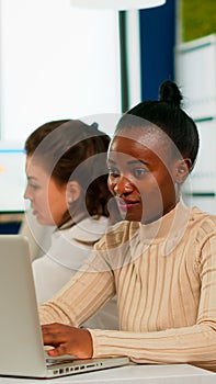 Cheerful african business lady typing on laptop and smiling sitting at desk