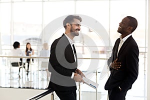 Cheerful african businessman laughing at funny joke of caucasian