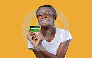 Cheerful African Female Showing Credit Card Posing Over Yellow Background