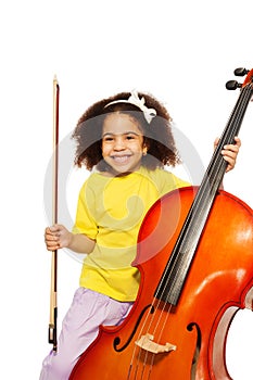 Cheerful African girl holds cello with fiddlestick