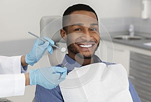Cheerful african guy in dentist chair, visiting modern clinic