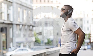 Cheerful african guy in headphones enjoying listening to music
