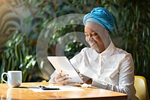 Cheerful african lady business advisor working online, using digital pad