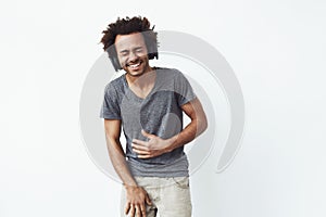 Cheerful african man in headphones laughing over white background. Closed eyes.