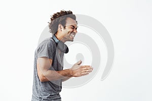 Cheerful african man with headphones laughing standing in profile over white background.