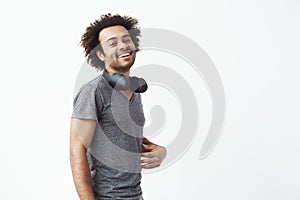 Cheerful african man with headphones smiling looking at camera over white background.