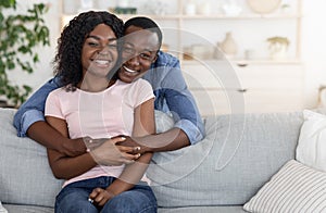 Cheerful african man hugging his smiling wife from behind