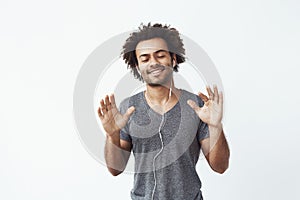 Cheerful african man listening to music in headphones dancing singing.