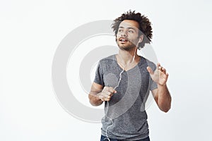 Cheerful african man listening to music in headphones dancing singing.
