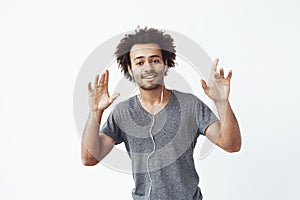 Cheerful african man listening to music in headphones dancing singing.