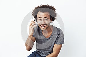 Cheerful african man smiling speaking on phone over white background.