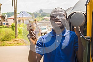 cheerful african man winner holding some money celebrating and jubilant standing next to an auto rickshaw taxi outdoor