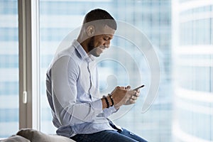 Cheerful African mobile phone user man using online app