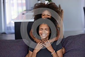 Cheerful african mom and kid daughter laughing embracing at home