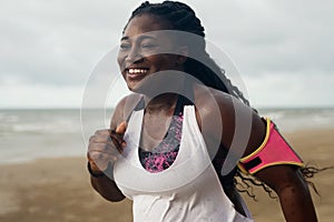 Cheerful african runner jogging during outdoor workout on beach