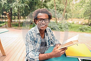 Cheerful african young man reading book outdoors