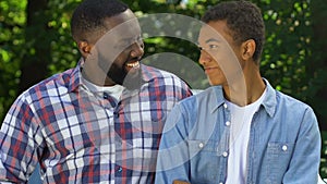 Cheerful afro-american dad giving car keys to teenage son, trustful relations