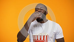 Cheerful Afro-American man eating popcorn and laughing out loud, comedy show