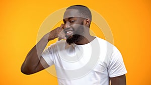 Cheerful Afro-American man showing call me gesture, getting acquainted on party photo