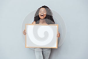 Cheerful afro american woman showing blank board