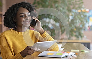 Cheerful afro businesswoman talking to client on phone