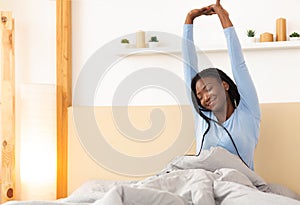 Cheerful Afro Lady Stretching Raising Arms Sitting In Bed