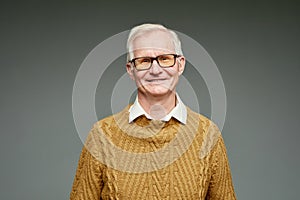 Cheerful aged grey haired man wearing brown knitted sweater