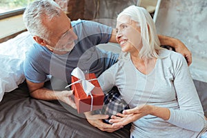 Cheerful aged loving couple holding a present