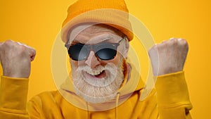 Cheerful aged man enjoying time in studio. Old guy raising hands indoors.