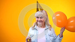 Cheerful aging woman with balloons celebrating birthday, positive attitude