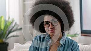 Cheerful alone young millennial African American woman smiling portrait at couch sofa happy ethnic girl in glasses wife