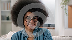 Cheerful alone young millennial African American woman smiling portrait at couch sofa happy ethnic girl in glasses wife