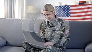 Cheerful american soldier woman making videocall on laptop pc at home, military