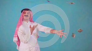 Cheerful Arab man with a mustache and traditional clothes with Audi ,throws money