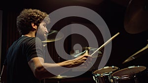Cheerful artist hitting drum cymbals in studio. Closeup drummer playing on stage
