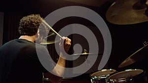 Cheerful artist hitting drum cymbals in studio. Closeup drummer playing on stage