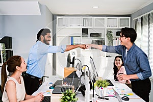 Cheerful Asian businessman partners making fist bump with a smile as a symbol of teamwork. Positive multi-ethnic business