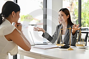 Cheerful Asian female lawyer meets with her female client in the office