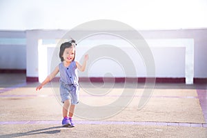 Cheerful Asian girl  playing and dancing in the warm sunshine with a bright smile. Happy baby concept. Baby age 2 years old.