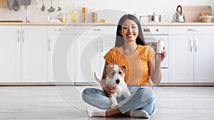 Cheerful asian lady with cute doggy showing pets supplement jar