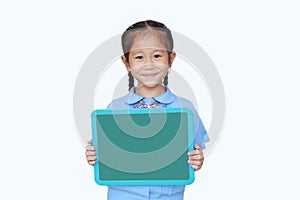 Cheerful Asian little child girl in school uniform holding blank board over white background. Kid with empty green blackboard.