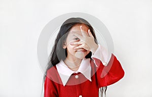 Cheerful Asian little girl covering her eyes by hand over white background