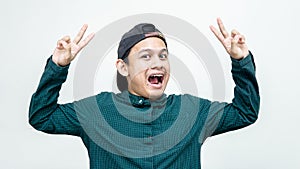 Cheerful Asian Malay man with cap showing v-sign or peace having fun