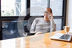 Cheerful asian male small business owner talking on phone with customer while sitting in office. Copy space. photo