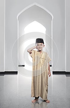 Cheerful asian muslim kid wearing traditional dress praying