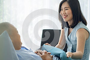 Cheerful asian nurse smiling and covering a blanket to elderly in nursing home