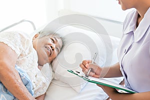 Cheerful Asian nurse talking with elderly patient for monitoring and check up. nurse giving consoling to senior and encourage.
