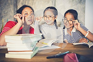 Cheerful asian teenager wearing eye glasses with school book in home living room